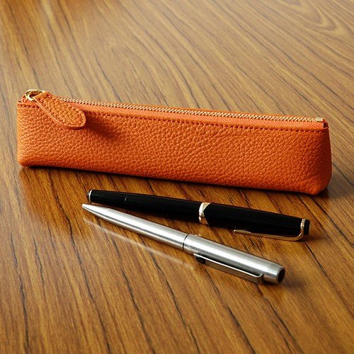 机に置かれた2本のペンとオレンジ色のドイツシュリンクスリムペンケース
